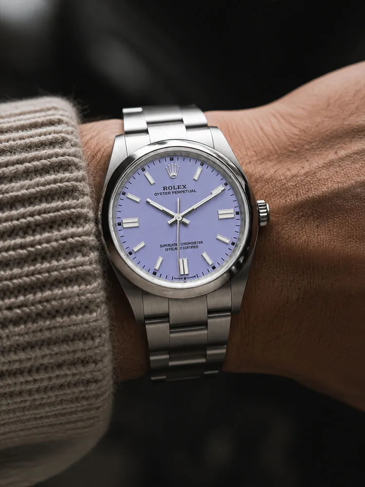 Rolex Oyster Perpetual watch with a lavender dial and stainless steel bracelet worn on the wrist.