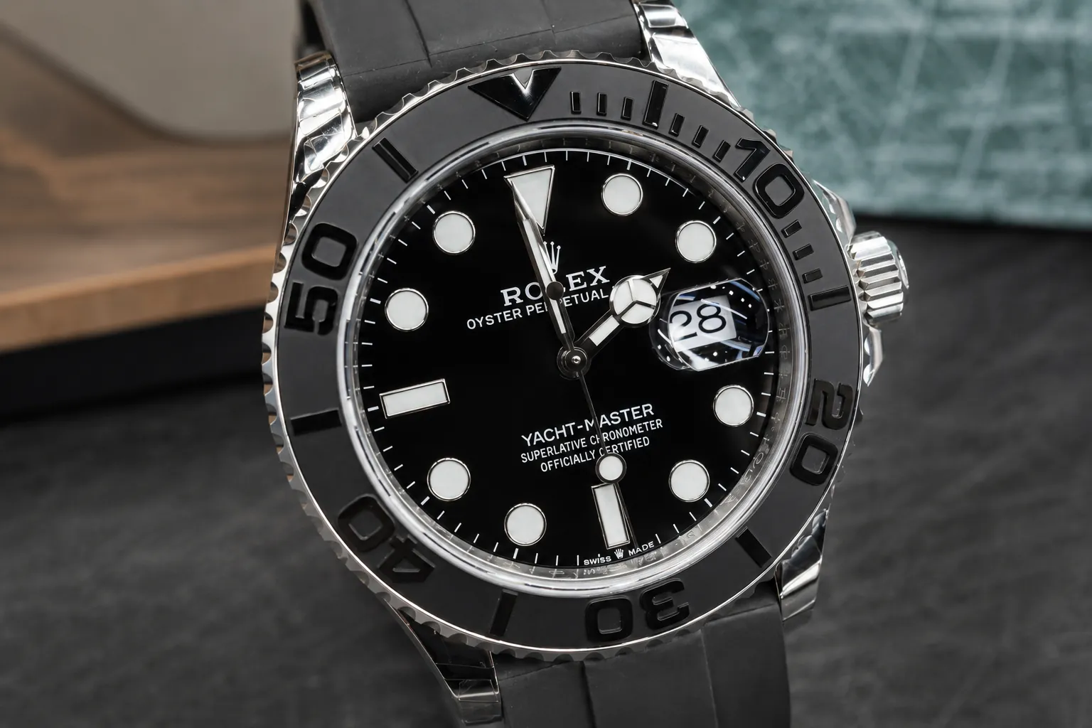 Rolex Yacht-Master black dial luxury watch close-up product photo with rubber strap, date window, luminous markers and ceramic bezel details