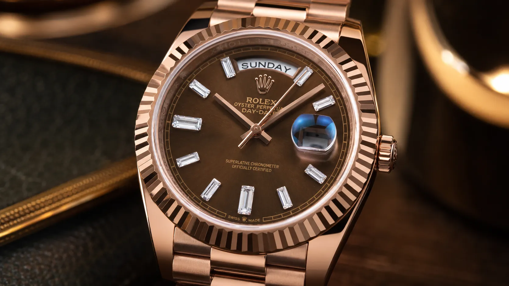 Rose gold Rolex Day-Date watch close-up product photo with chocolate dial, fluted bezel, baguette hour markers, day display and magnified date window