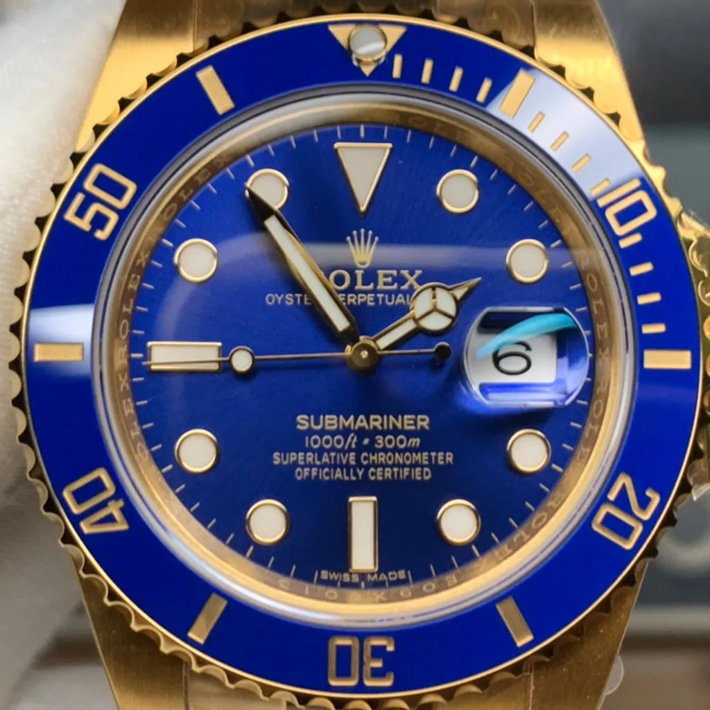 Rolex Submariner close-up with a blue dial, blue bezel, gold case, date magnifier showing 6, and gloved hand.