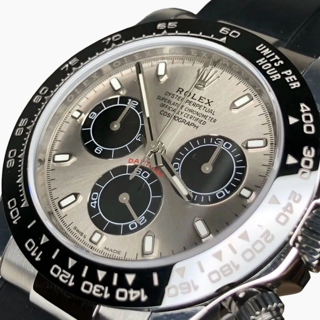 Close-up of the Rolex Daytona chronograph with a silver "Panda" dial, featuring a black tachymetric bezel, a three-register chronograph layout, and a black rubber strap.