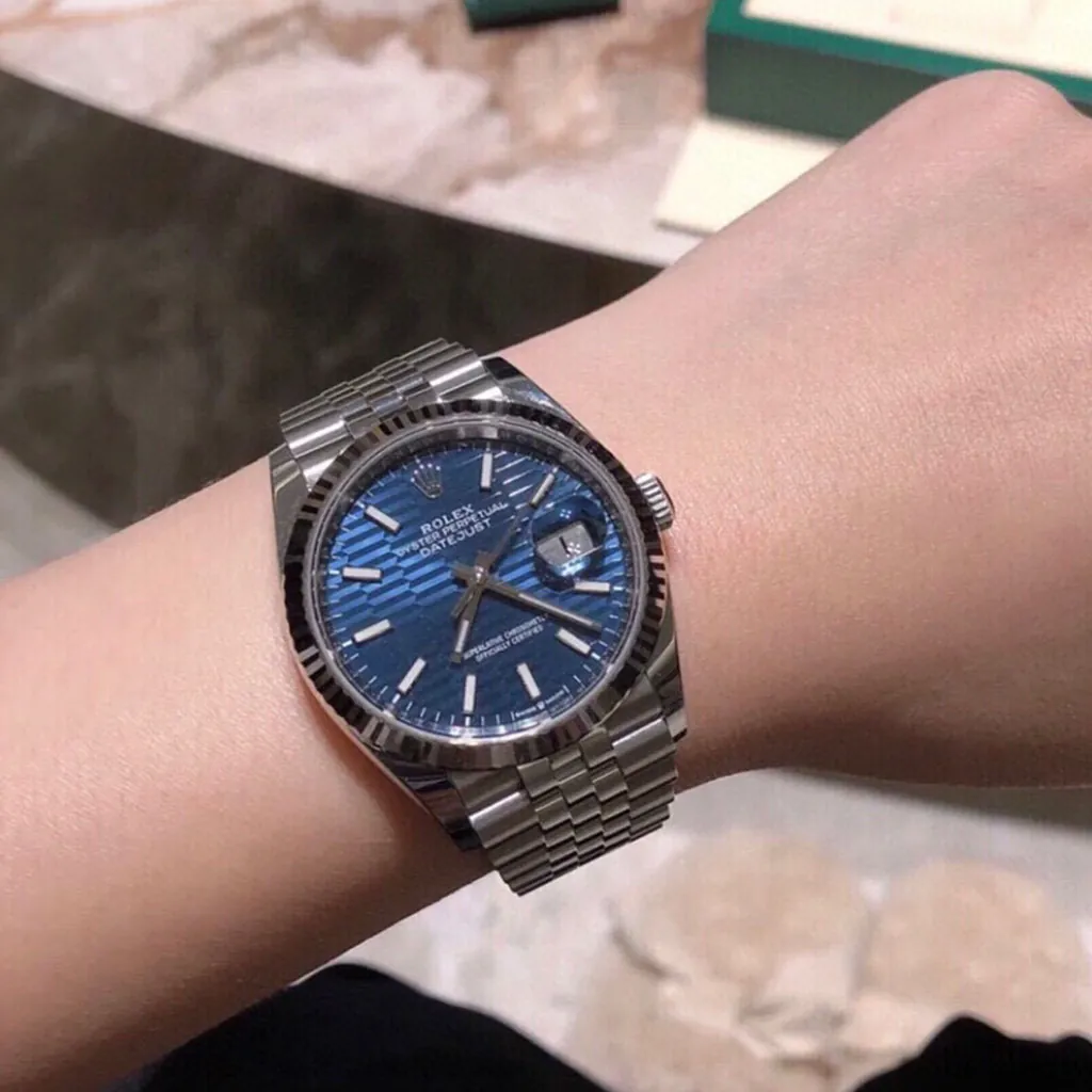 Rolex Datejust blue motif dial watch on wrist with fluted bezel, Cyclops date window, and stainless steel Jubilee bracelet