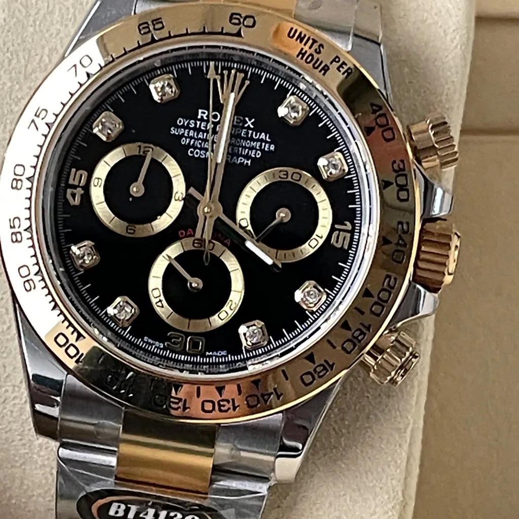 Rolex Cosmograph Daytona two-tone watch with black diamond dial and gold tachymeter bezel.